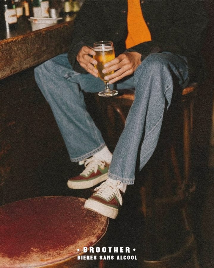 Verre de bière BROOTHER tenu par une personne assise au comptoir d'un bar — bière sans alcool au bar
