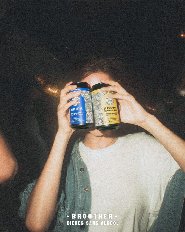 Deux canettes BROOTHER NEIPA et Hoppy Blonde Ale tenues devant les yeux lors d'une soirée entre amis