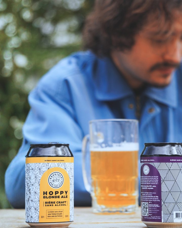 Canettes BROOTHER Hoppy Blonde Ale et Stout avec une chope de bière sur une table en extérieur