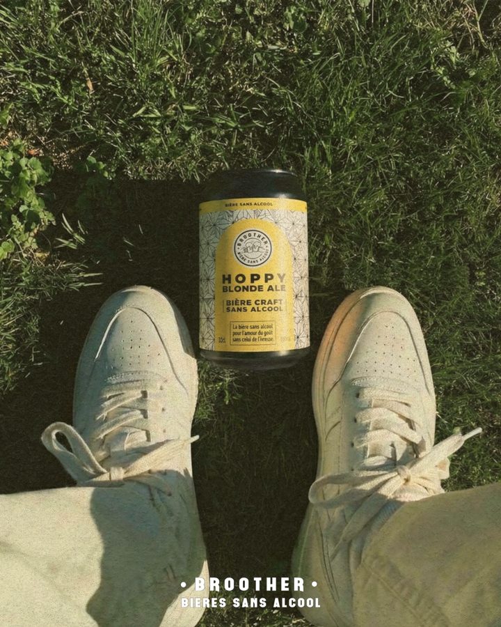 Canette BROOTHER Hoppy Blonde Ale posée sur l'herbe entre deux baskets blanches — bière blonde sans alcool